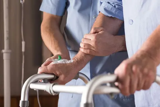 Healthcare person gives support to patient in walking